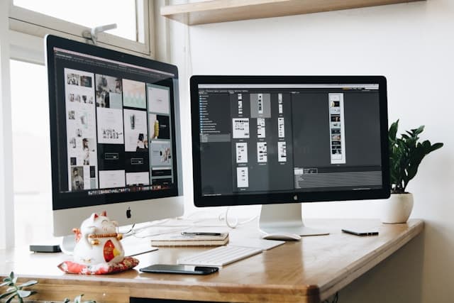 Web design workspace with dual monitors showing design work in progress